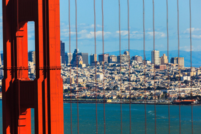 View of San Francisco as seen through the vertical cables of the golden gate bridge